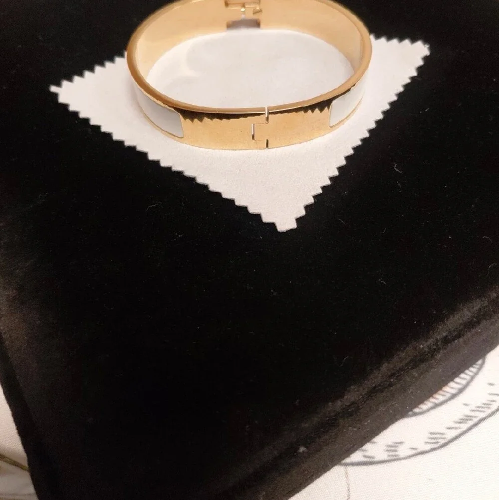 HERMES Gold and White Enamel Click H Bracelet with Signature H Accent.